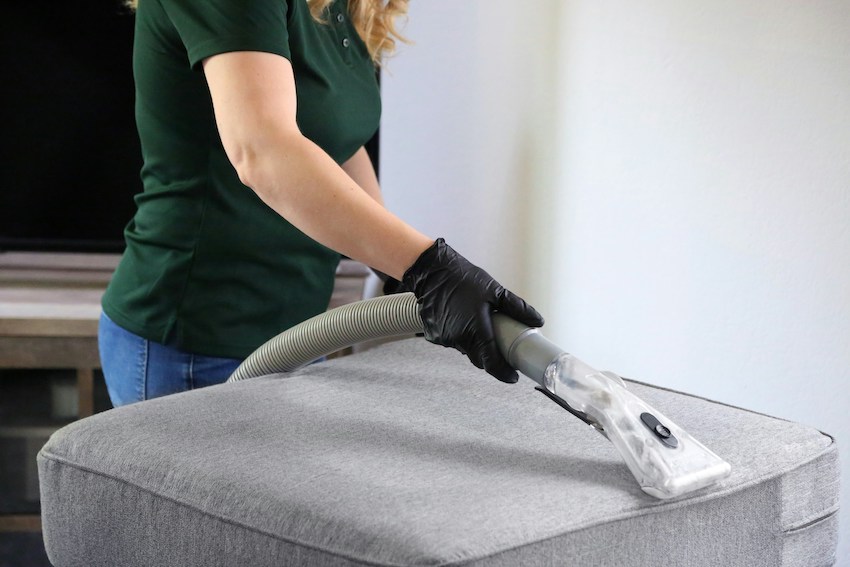 Benefits of Hiring a Professional House Cleaner. Person deep cleaning sofa cover. 